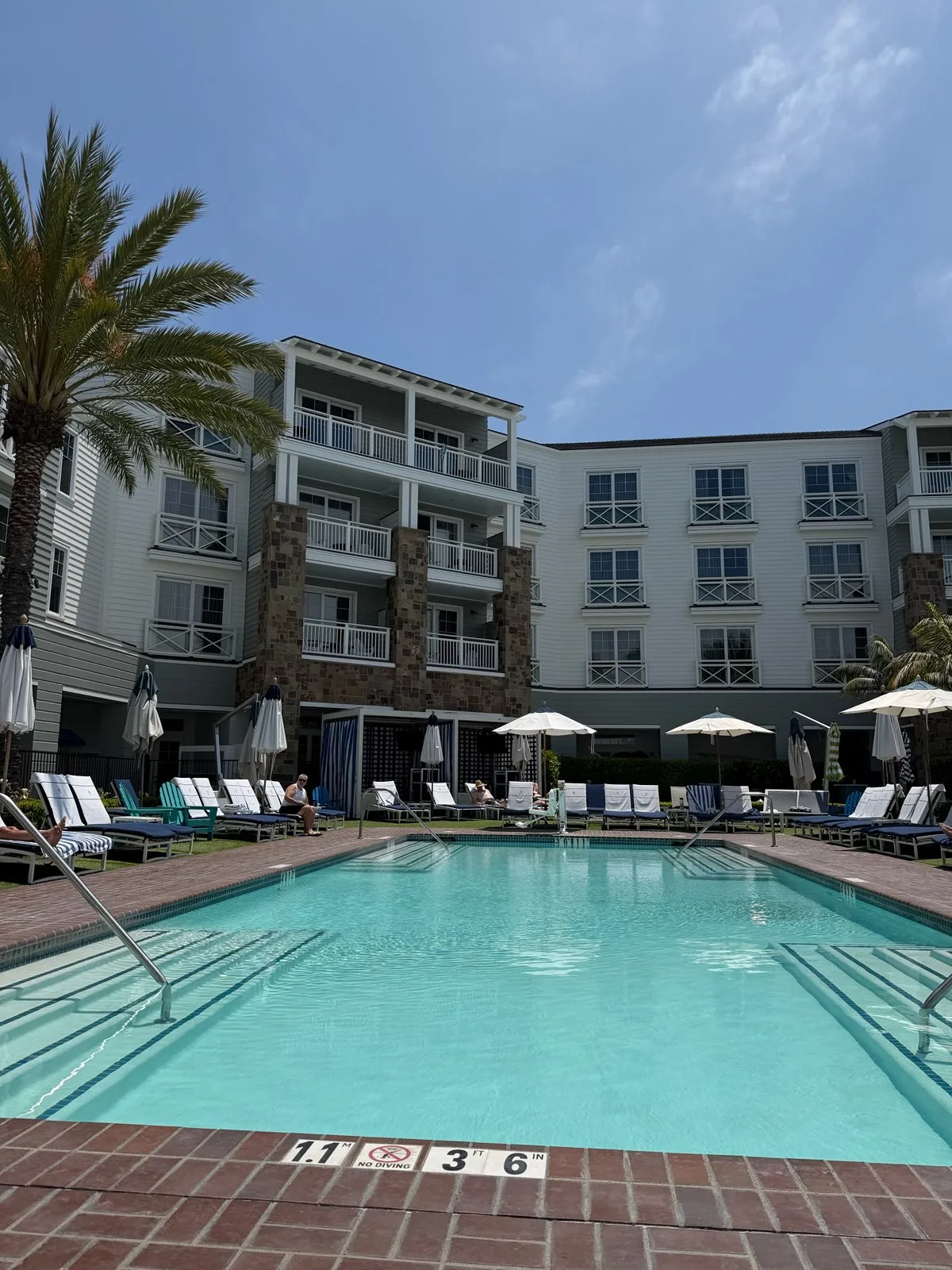 The hotel courtyard pool lined with loungers and cabanas, main building behind
